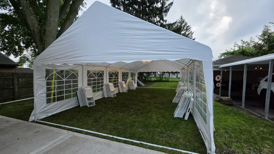 White event tent in a residential backyard with clear-window walls