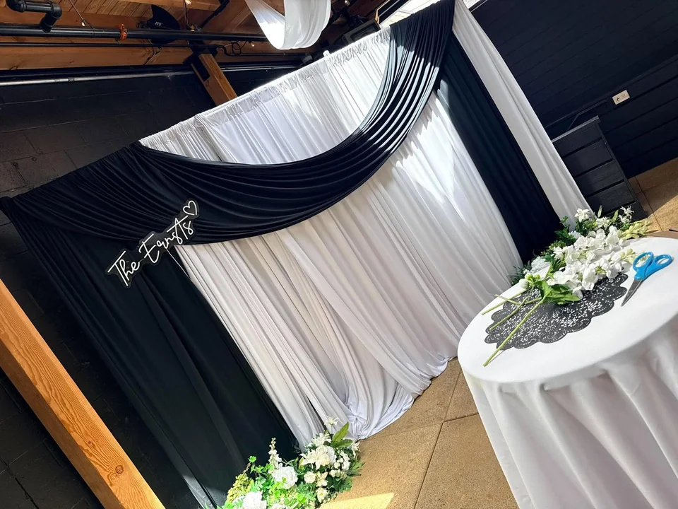 Black and white fabric draping behind a styled table with white flowers and greenery