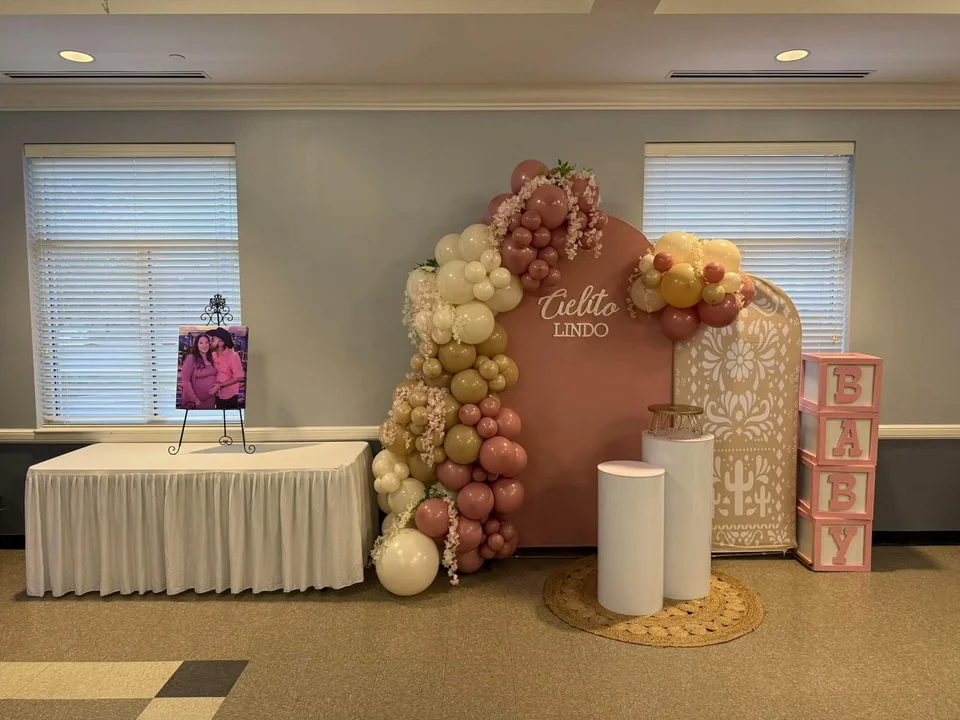 A blush Cielito Lindo backdrop with cream, mauve and gold balloons, delicate flowers and display plinths