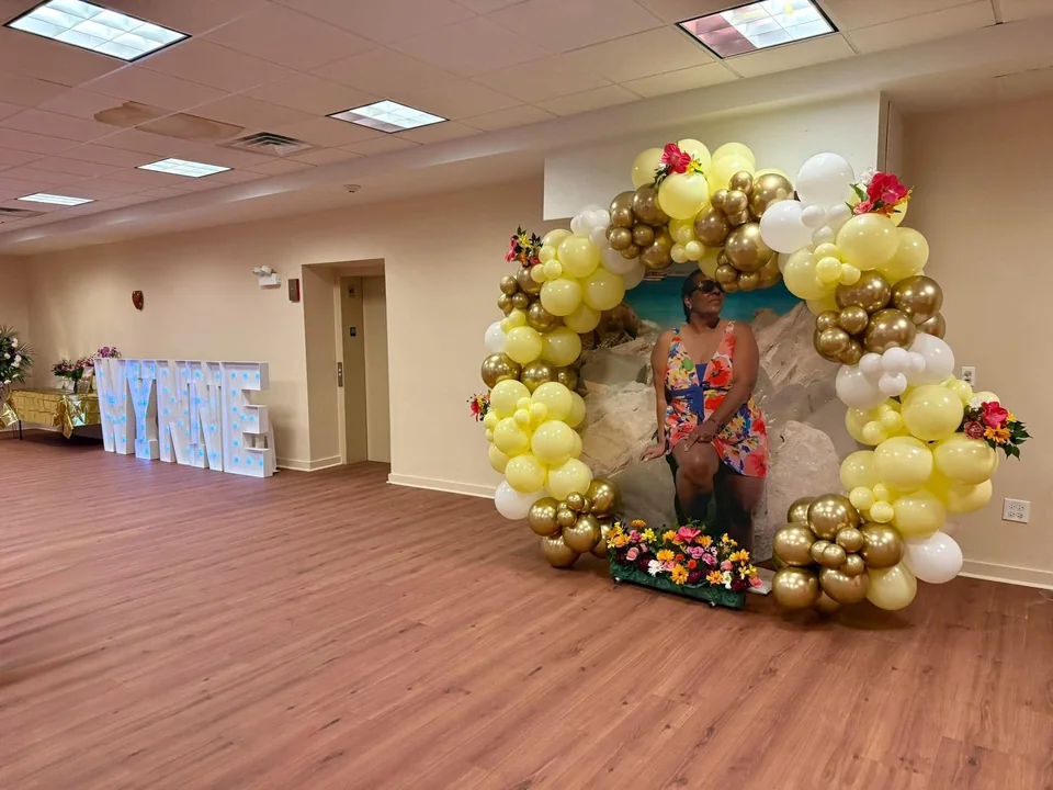 A circular gold and ivory balloon installation with floral accents framing a personalized celebration display