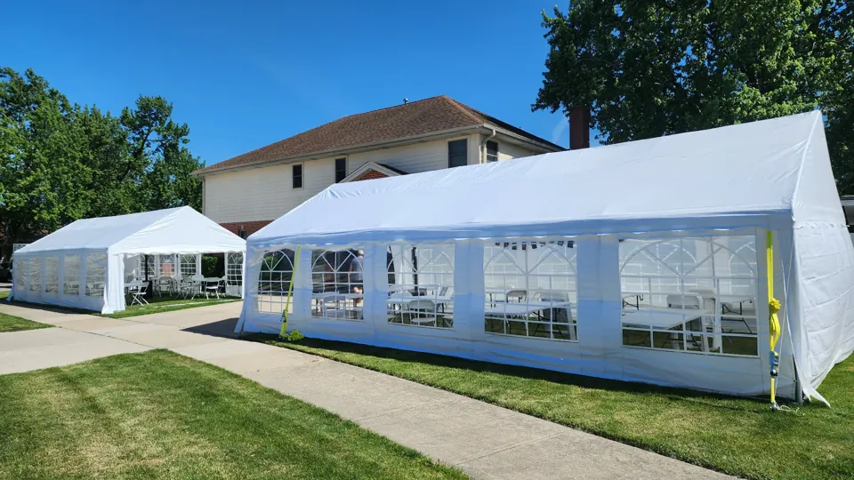 Several white event tents with clear-window sidewalls installed across an outdoor space