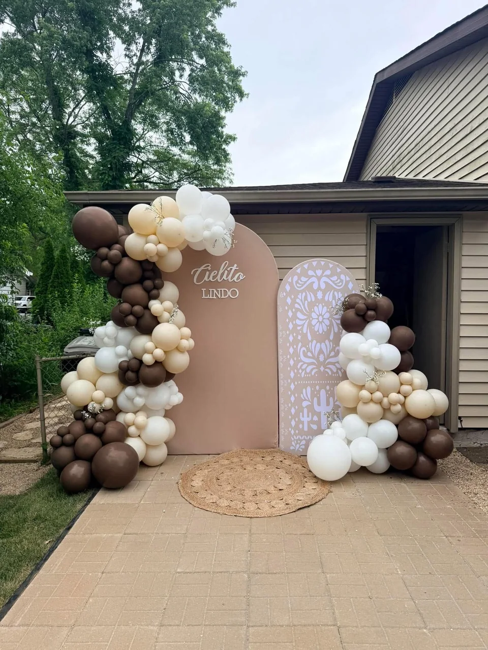 Cielito Lindo arch backdrops with an intricate white pattern, woven rug and cream, white and chocolate balloons