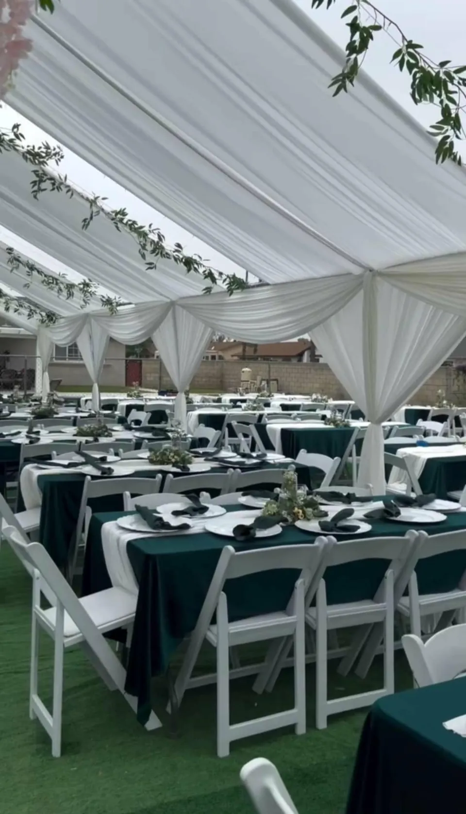 Premium white resin garden chairs with green table linens and white ceiling draping