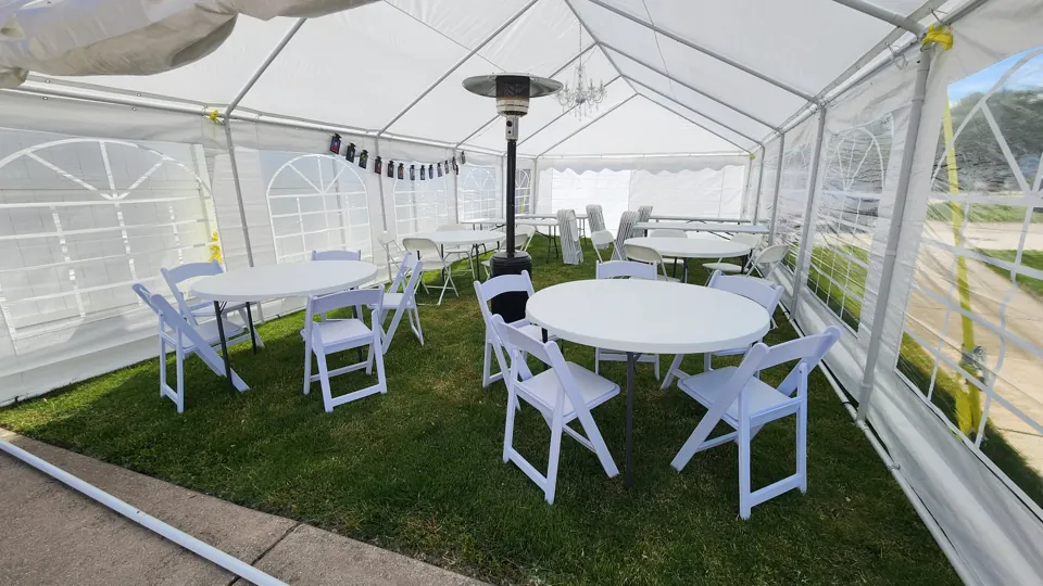 Round white tables and classic folding chairs inside a window-wall tent