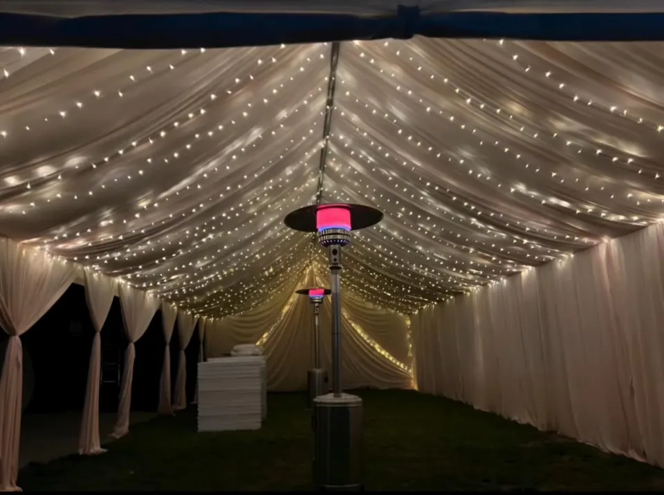 Twinkle lights and white ceiling draping inside a tent with a patio heater